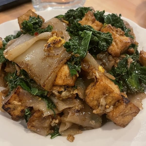 Close-up of Thai Time's Pad See Ew with wide noodles, tofu, and kale.