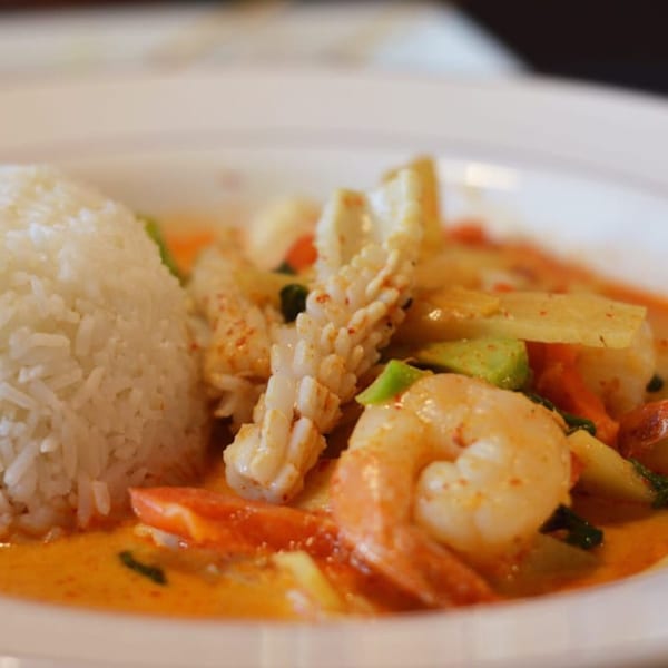Thai Time's red curry with shrimp, squid, and vegetables, served with a side of white rice.